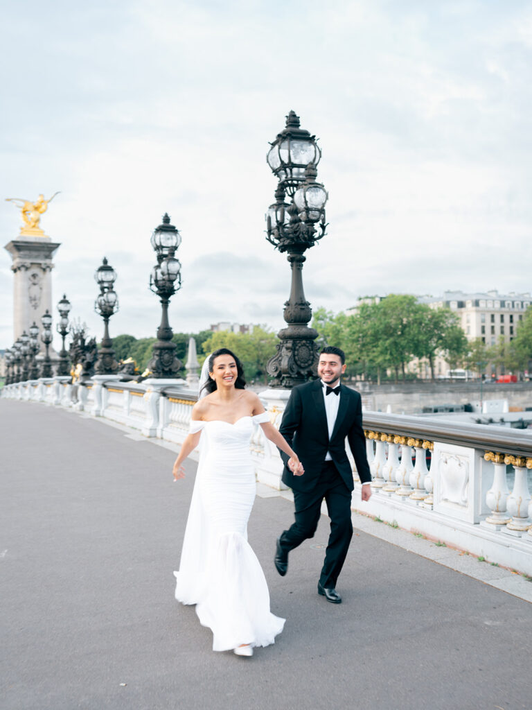 Paris wedding photo of a married couple running on Pont Alexandre III in Paris